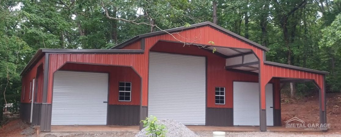A red barn with a large white door surrounded by trees.