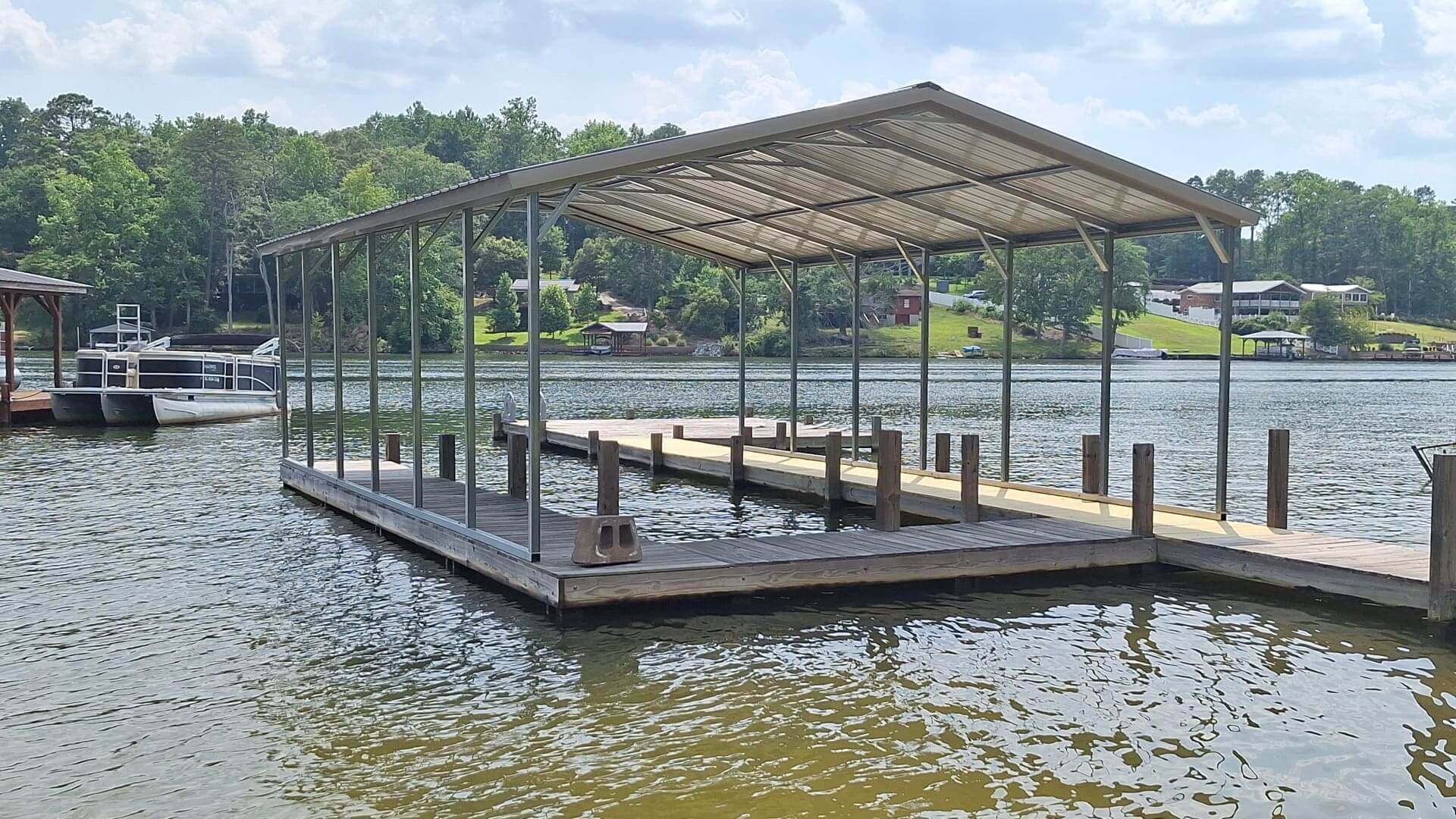Empty covered boat dock on a calm lake near wooded shore.