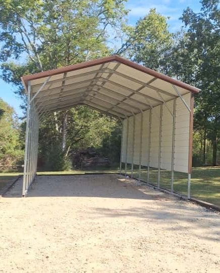 Metal carport structure in a wooded area.